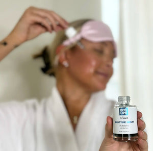 A customer is holding the nighttime serum and applying the dropper to her cheek