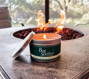 Man preparing food outdoors with a Bug Soother candle in the foreground.