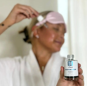 A customer is holding the nighttime serum and applying the dropper to her cheek.