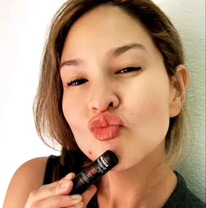 Woman holding lip tint showing how the color looks when applied. 